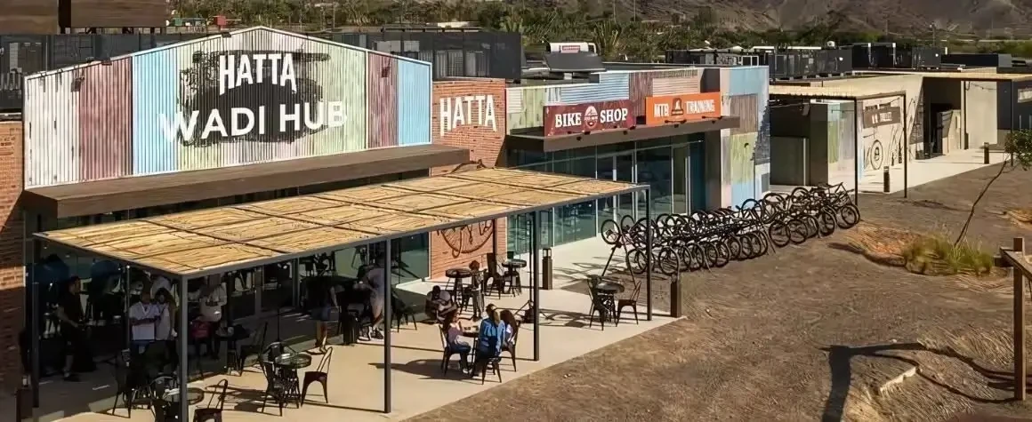 Hatta Wadi Hub with people relaxing, shops, and bicycle rentals