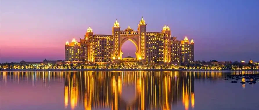 Dusk view of the Atlantis Hotel in Dubai, showcasing its lights amidst the sparkling night scenery of Palm Jumeirah.