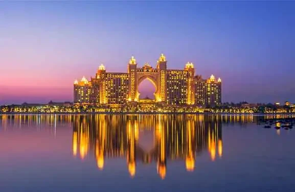 Dusk view of the Atlantis Hotel in Dubai, showcasing its lights amidst the sparkling night scenery of Palm Jumeirah.