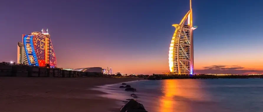 Iconic Burj Al Arab hotel in Dubai, featuring its distinctive sail-like design, towers over the surrounding landscape.