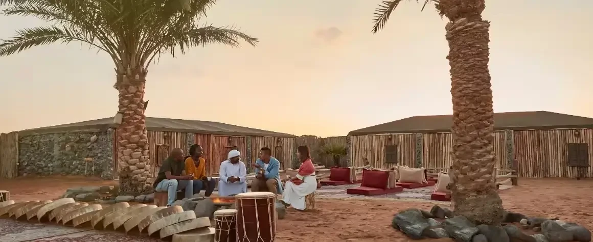 Group relaxing under palm trees during evening desert safari Dubai