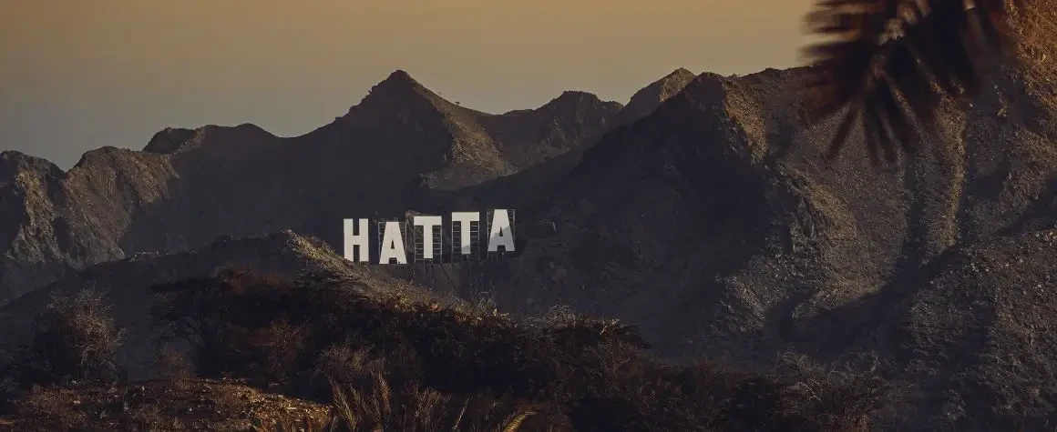 Mountain view with 'Hatta' sign carved into the rocks during Hatta Dubai Tour