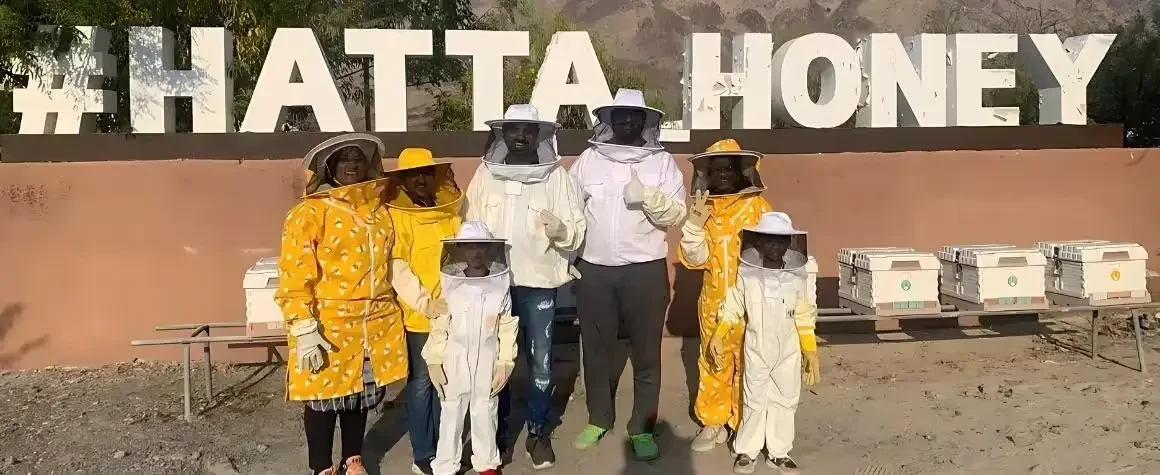 Family posing in front of 'Hatta Tour' sign at a popular photo spot