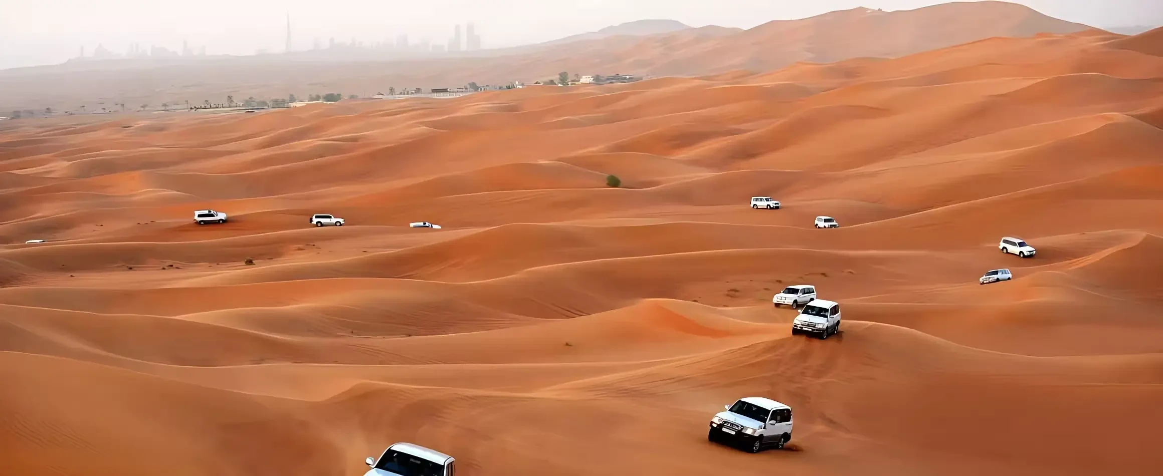 Fleet of 4x4 vehicles crossing Dubai desert during premium safari tour