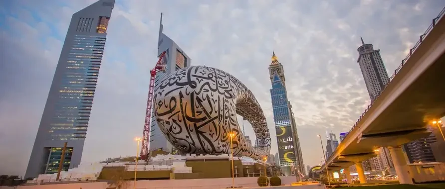 A large sculpture of a giant snake prominently displayed outside a museum in Dubai, surrounded by urban architecture.