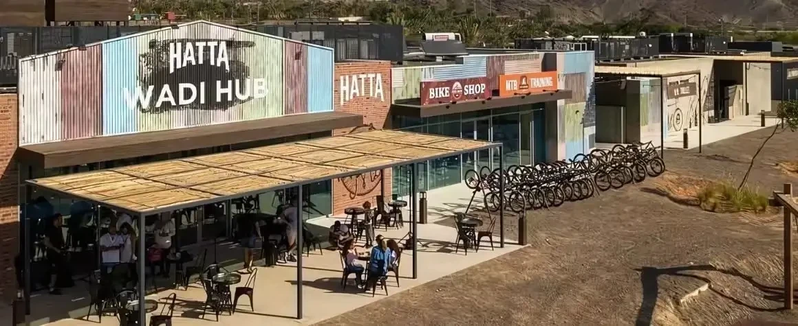 Hatta Wadi Hub with people relaxing, shops, and bicycle rentals