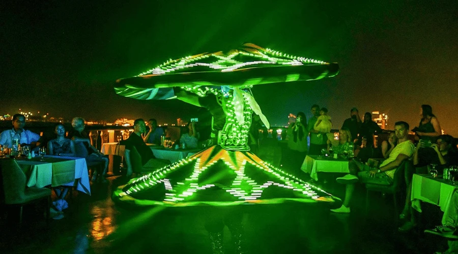 Traditional Tanoura dancer performing with illuminated LED costume for guests on a Dubai Marina evening dhow cruise.
