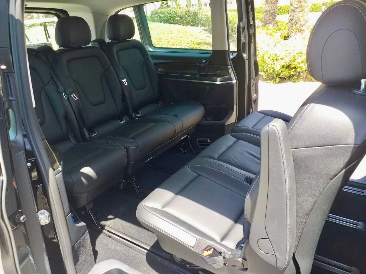 Spacious rear passenger cabin of a Mercedes V-Class with premium black leather seats in a face-to-face configuration.