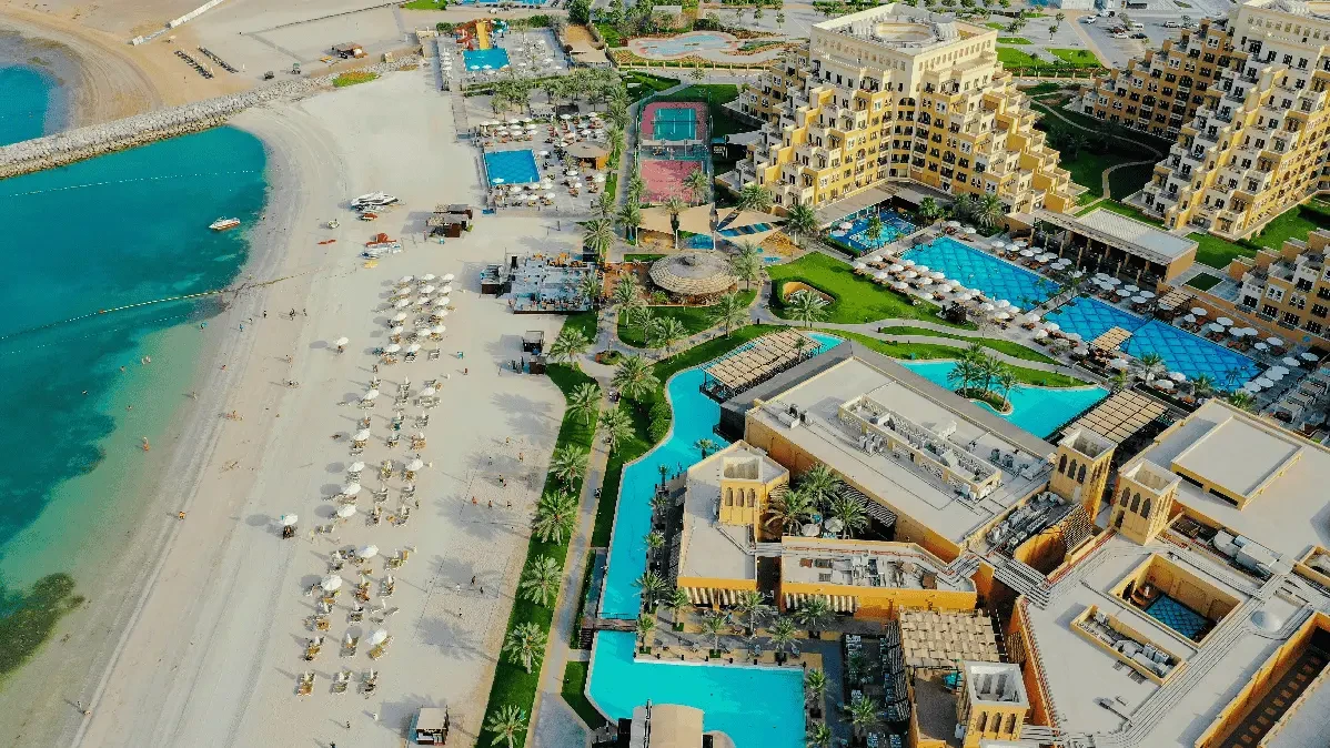 A scenic view of the beach and resort area in Ras Al Khaimah, showcasing clear waters and palm trees.