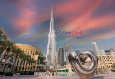 The Burj Khalifa tower standing tall against a vibrant sunset sky near the famous heart sculpture in Dubai.