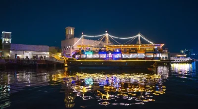 Traditional Dubai dhow cruise boat with colorful lights on the creek