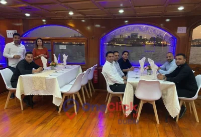 Friends and families enjoying a formal dinner experience inside the climate-controlled lower deck of a dhow boat.