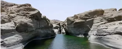 River flowing between rugged Hatta mountains under clear blue sky