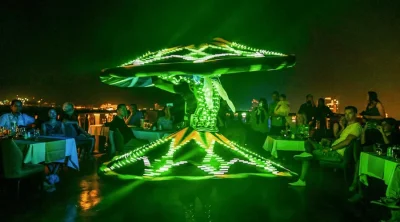 Traditional Tanoura dancer performing with illuminated LED costume for guests on a Dubai Marina evening dhow cruise.