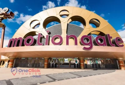 The iconic golden film reel entrance gate of Motiongate Dubai theme park under a blue sky.