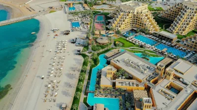A scenic view of the beach and resort area in Ras Al Khaimah, showcasing clear waters and palm trees.