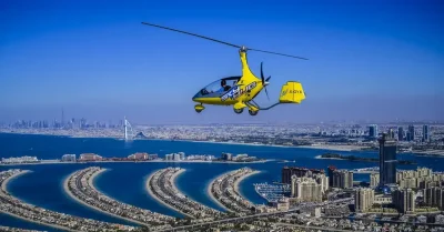 A yellow helicopter soars above a city and a vast body of water, highlighting Dubai's beauty during a short aerial tour.
